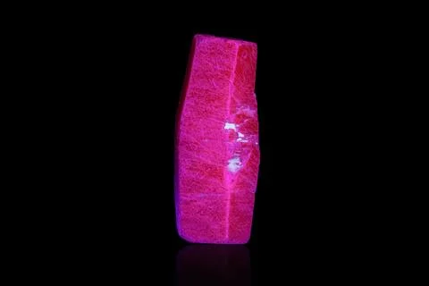 Macro mineral stone ruby under ultraviolet light on a black background Foto stock