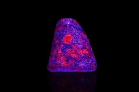 Macro mineral stone ruby under ultraviolet light on a black background Foto stock