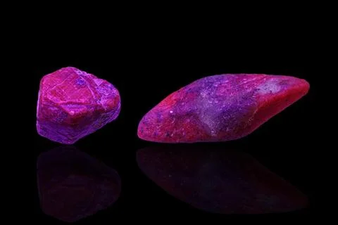 Macro mineral stone ruby under ultraviolet light on a black background Stock Photos