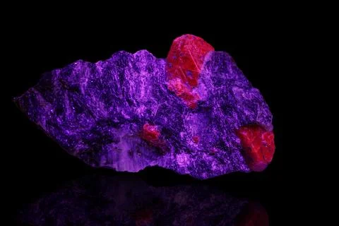 Macro mineral stone ruby under ultraviolet light on a black background 写真素材