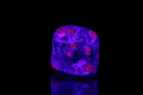 Macro mineral stone ruby under ultraviolet light on a black background 스톡 사진