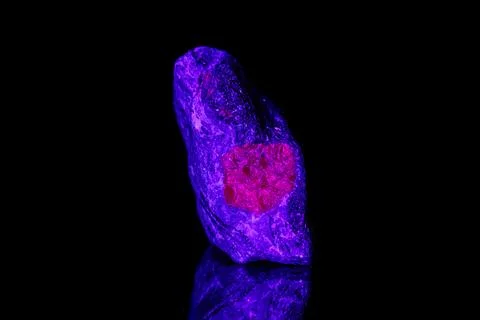 Macro mineral stone ruby under ultraviolet light on a black background 스톡 사진