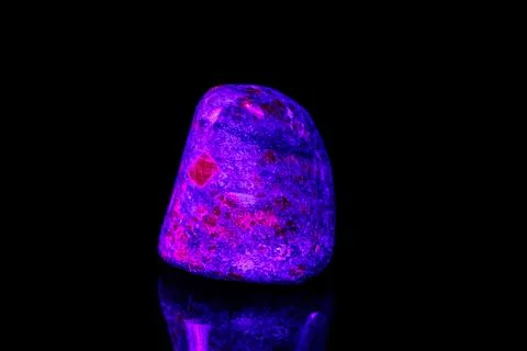 Macro mineral stone ruby under ultraviolet light on a black background 写真素材