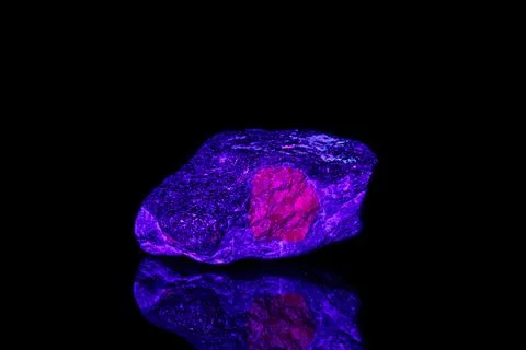 Macro mineral stone ruby under ultraviolet light on a black background Stock Photos