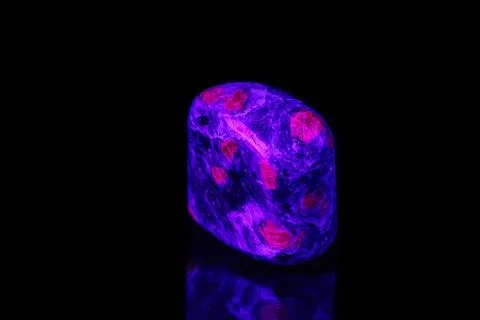 Macro mineral stone ruby under ultraviolet light on a black background 스톡 사진