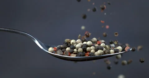 Macro of mixed peppercorn seeds falling down silver spoon on dark background Stock-Footage 268979816