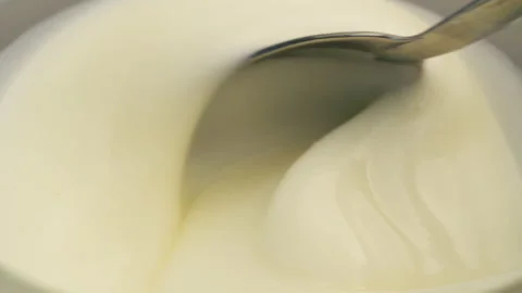Macro of mixing yogurt with a spoon in a cup. Stock Footage 221787055