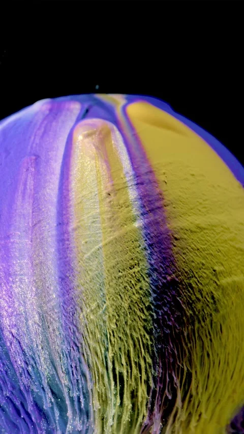 Macro motion of purple and yellow paint stretching into fibrous drips against bl Stock Footage 340780990