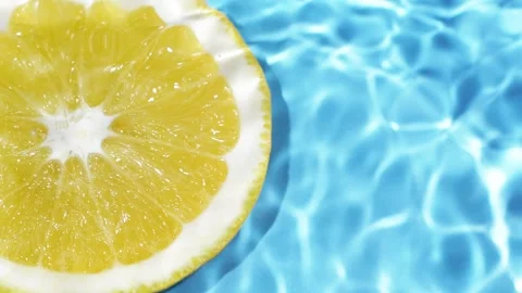 Macro orange fruit slice and blue water surface texture with ripples and splash Видео 165640340
