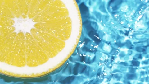 Macro orange fruit slice and blue water surface texture with ripples and splash Stock Footage 168789700