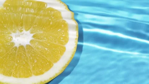 Macro orange fruit slice and blue water surface texture with ripples and splash Stock Footage 170104014