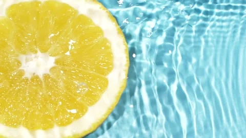 Macro orange fruit slice and blue water surface texture with ripples and splash Stock Footage 170590886