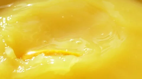 Macro orange fruit slice falling down into fresh orange juice drink, slow motion Stockbeeldmateriaal 145300451
