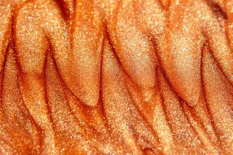 Macro orange glitter texture with shimmering metallic waves and abstract sparkle Stock Photos