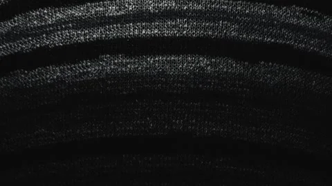Macro pan of black textured knit fabric catching moody cinematic light across cu Stock Footage 337025545