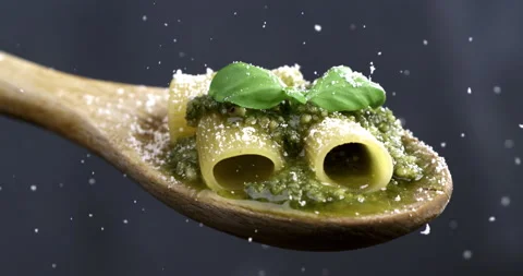 Macro of parmesan cheese being grated on pasta with green pesto Genovese sauce Stock Footage 268880621
