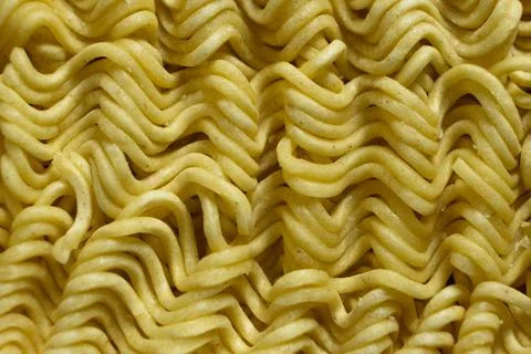 Macro pattern of dry yellow wavy instant noodles Stock Photos