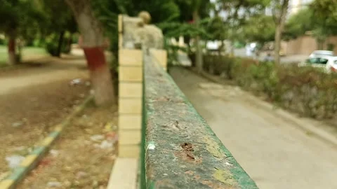 Macro perspective rustic green painted metal fence rail park trees blur Stock Footage 341683533