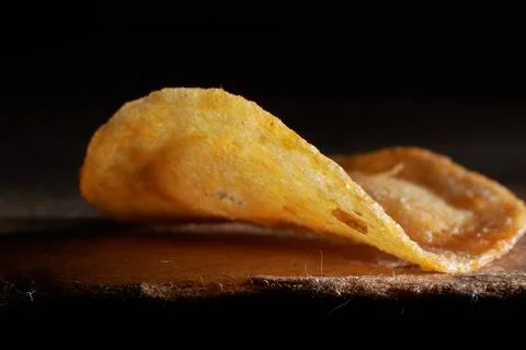 Macro photo of chips on a wooden table, a slice of fried potatoes, beer snacks Stock Photos