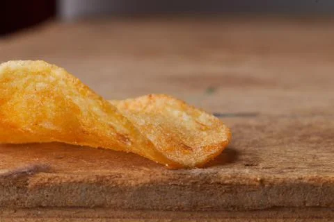 Macro photo of chips on a wooden table, a slice of fried potatoes, beer snacks Stock Photos