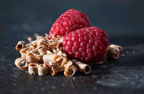 Macro photograph of two raspberries with chocolate shavings on a dark rustic Stock Photos