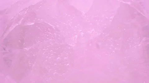 Macro pink broken ice texture with splashing water surface, drops and ripples Stockbeeldmateriaal 235969590