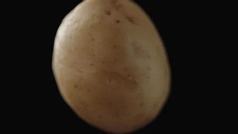 Macro, potato tuber in turning motion on a black background Stock Footage 225311270