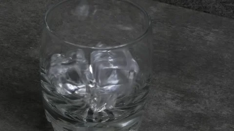 Macro puts crystal ice cubes in a glass while preparing an alcoholic cocktail Stock Footage 241602384