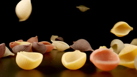 MACRO: Raw colour conchiglie pasta fall on a black table, Slow motion Stock Footage 181799175