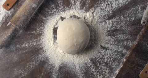 Macro of raw loaf of dough falling with flour dust splashes on table in bakery Stock Footage 268204189