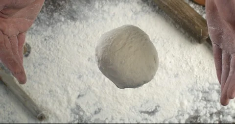 Macro of raw loaf of dough falling with flour dust splashes on table in bakery Stock Footage 268802764