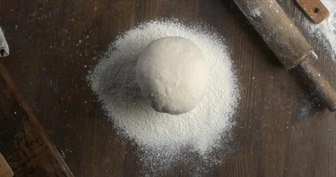 Macro of raw loaf of dough falling with flour dust splashes on table in bakery Stock Footage 268802773
