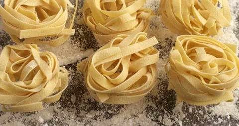 Macro of raw pasta farfalle bouncing with flour dust on table in bakery kitchen Stock Footage 268826355