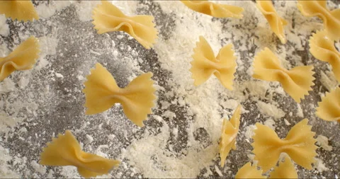 Macro of raw pasta farfalle bouncing with flour dust on table in bakery kitchen Stock Footage 268829593