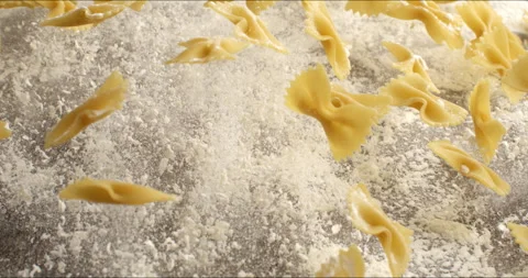 Macro of raw pasta farfalle bouncing with flour dust on table in bakery kitchen Stock Footage 268830252