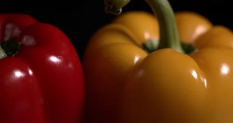 Macro red and yellow bell peppers lie on a table on a black background Stock Footage 130359900