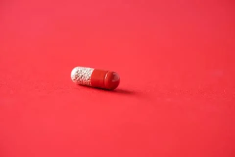 Macro of red capsules on red background. Copy space. Bunch of drugs, cold flu Stock Photos