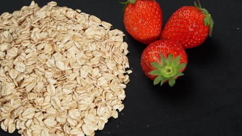 Macro Rotating Rolled Oats with Three Fresh Strawberries on Black. Stock-Footage 333046634
