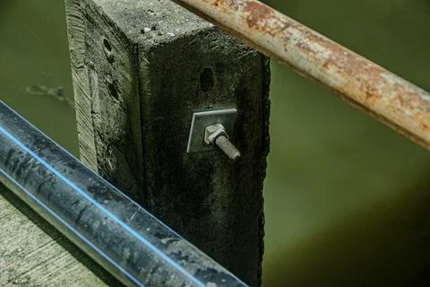 Macro of rusty iron bolt nut joint on streetlight pole concrete base at n Stock Photos