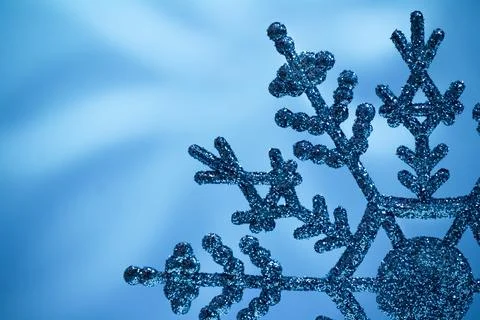 Macro shiny snowflake on blue blurred background. Merry Christmas card. Cop.. Stock Photos