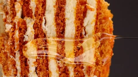 Macro shoot of liquid honey falling over cake. 100fps, vertical 動画素材 182244137