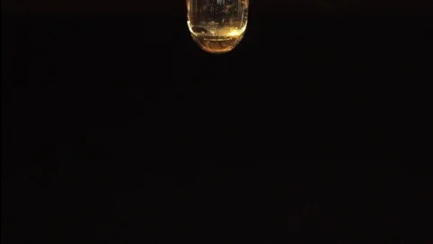 Macro shoot of thick liquid drop of oil or honey falling over black background Stock Footage
