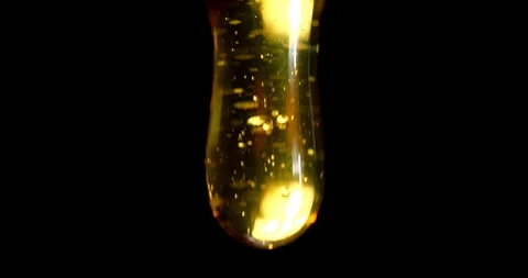 Macro shoot of thick liquid drop of honey or oil falling on black background Stock Footage 113940545