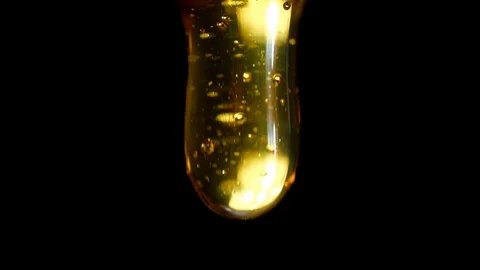Macro shoot of thick liquid drop of honey or oil falling on black background Stock-Footage 113940577