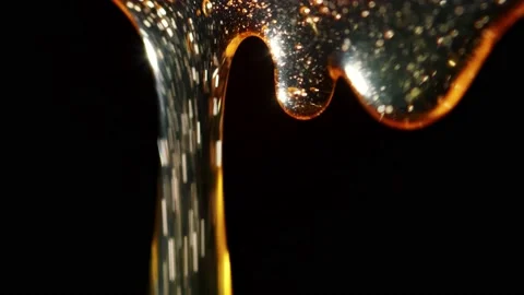 Macro shoot of thick liquid drop of oil or honey falling over black background Stock Footage 143353476