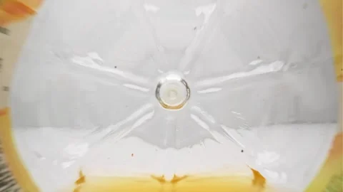 Macro shoot throught orange juice bottle probe lens Stock Footage 247649253