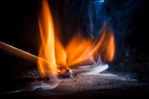 Macro shooting of a burning match with a flame of fire and smoke on a black b Stock Photos