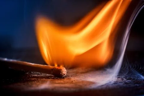 Macro shooting of a burning match with a flame of fire and smoke on a black b Stock Photos
