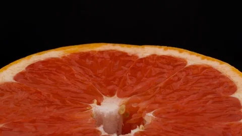 Macro shooting of a half cut pink grapefruit. Rotating. Isolated on the black Stock Footage 97342125