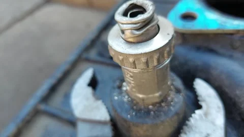 Macro shot of adjustable pliers gripping a metal valve component with a spring Stock Footage 336482690